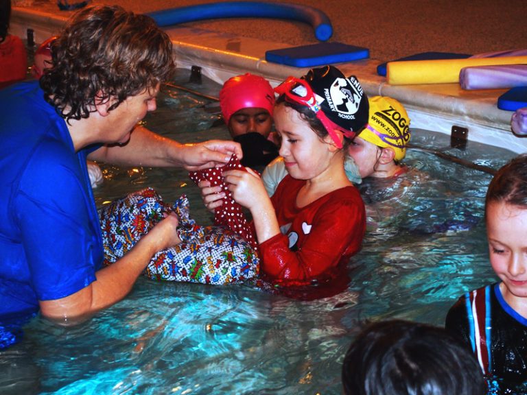Teacher helps a child during swimming lesson