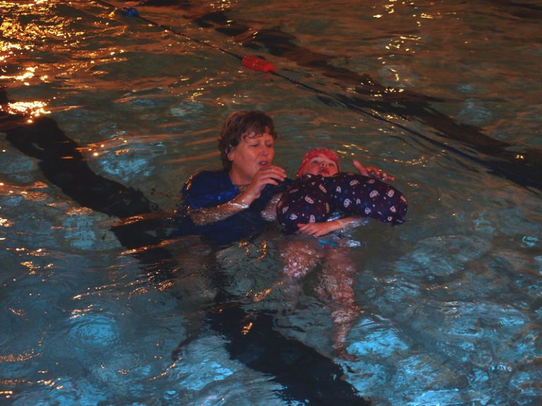 Teacher holds a child in the pool